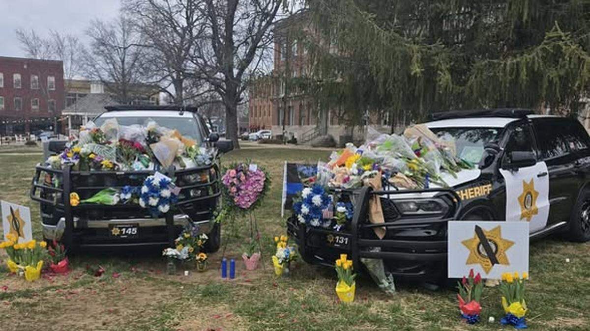 Flowers, wreaths and stuffed animals cover the patrol vehicles of Deputy Gabriel Ramirez, 30, and Deputy Michael Hislope, 40, outside the Christian County Courthouse in Ozark, Missouri. The two deputies were killed in the line of duty last month.