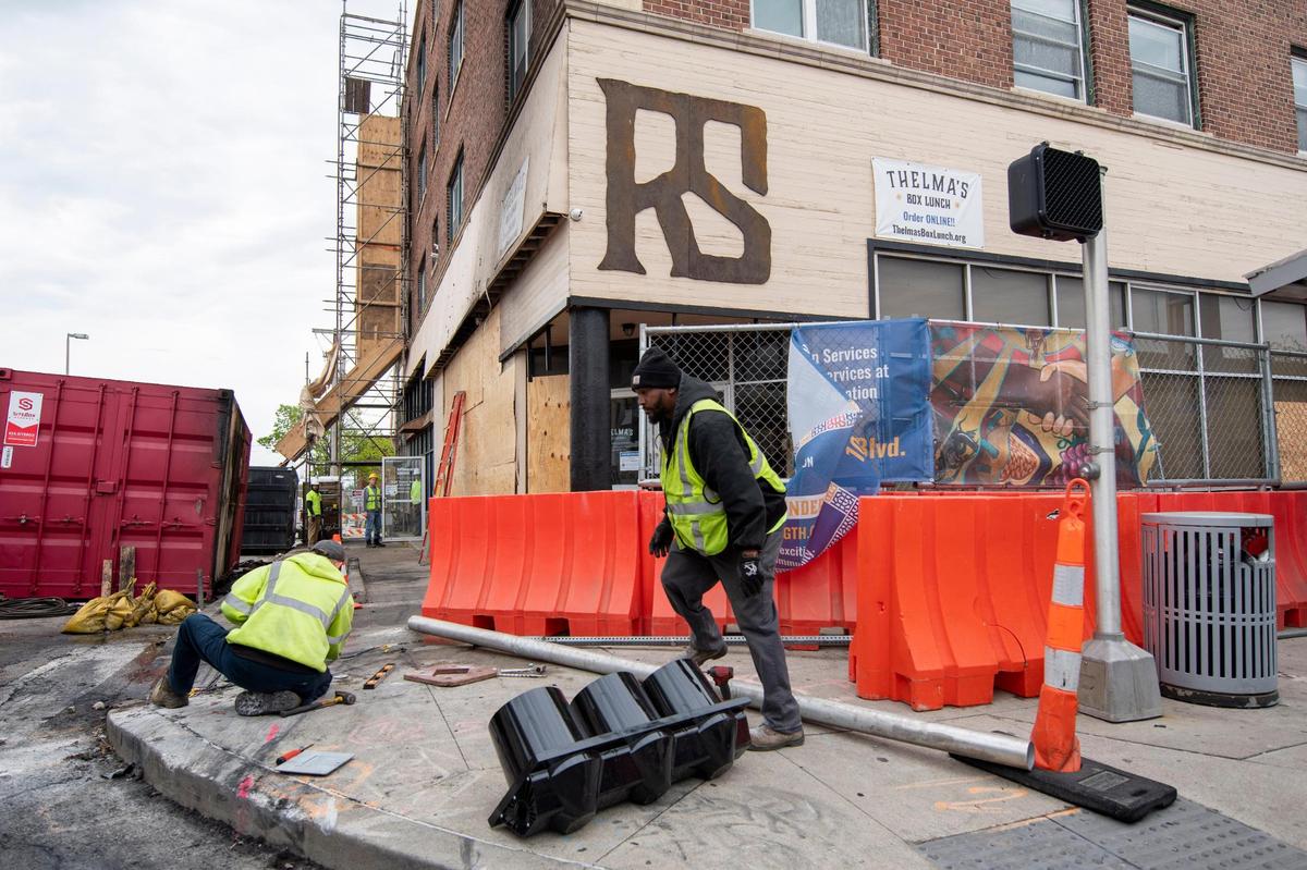 Kansas City Public Works employees repair a traffic signal damaged when a car crashed into a building late Sunday at 3101 Troost Ave. Two people were killed in the wreck.