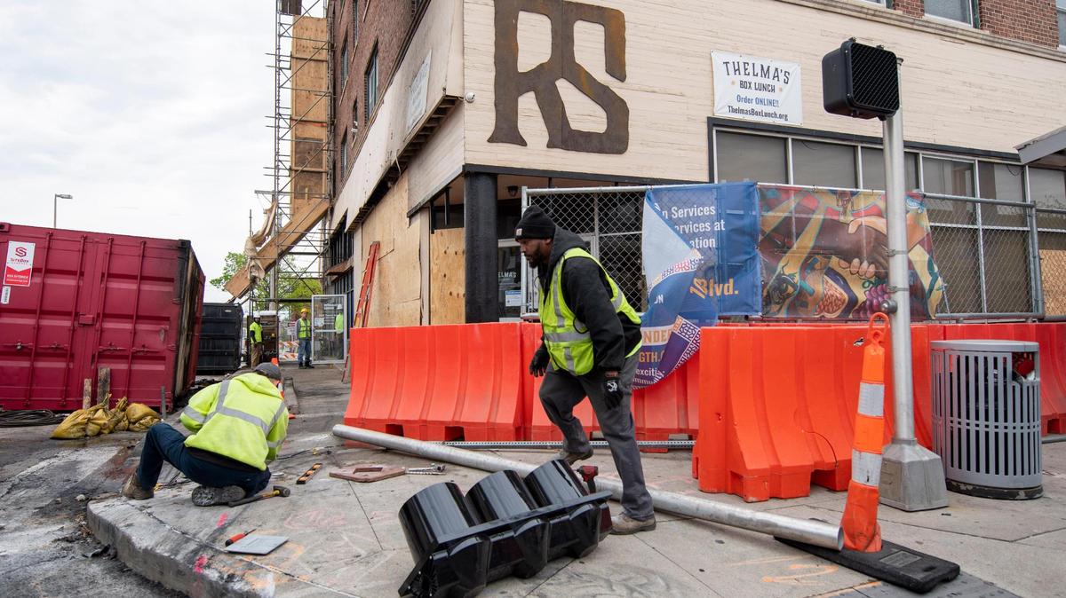 Kansas City Public Works employees repair a traffic signal damaged when a car crashed into a building late Sunday at 3101 Troost Ave. Two people were killed in the wreck.