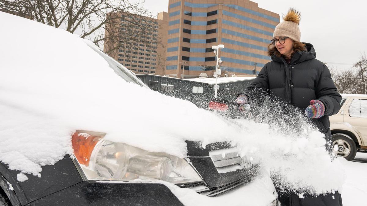 Kate Rezac, visiting from Omaha, brushes snow off her vehicle in Kansas City on Wednesday, Feb. 12. Kansas City was blanketed with snow overnight and into the early morning Wednesday.