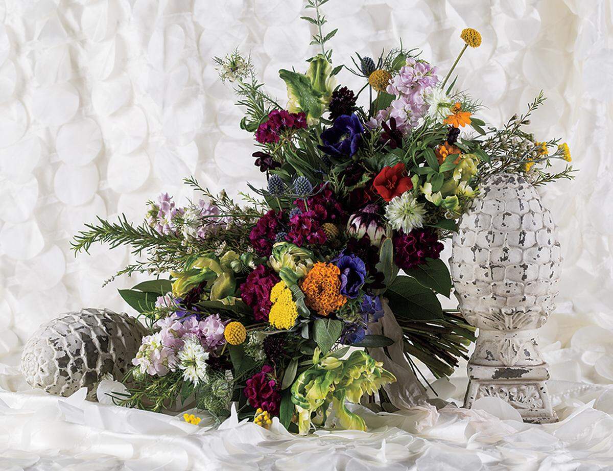 FREE AND EASY Traditional bouquets take a backseat to this cascading arrangement of chocolate cosmos, apple blossom stock, yellow parrot tulips, and nigella from Hitched Planning + Floral. Petal taffeta tablecloth available to rent from Ultrapom.
