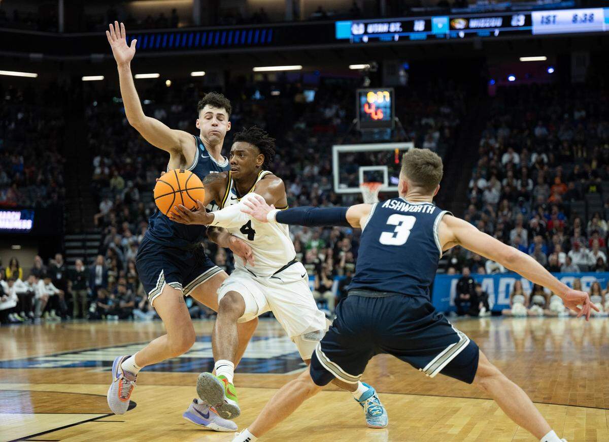 Missouri Tigers guard D’Moi Hodge (5) drives between Utah State Aggies guard Steven Ashworth (3) and Utah State Aggies forward Taylor Funk (23) during a game for the NCAA Tournament at Golden 1 Center in Sacramento, Thursday, March 16, 2023.