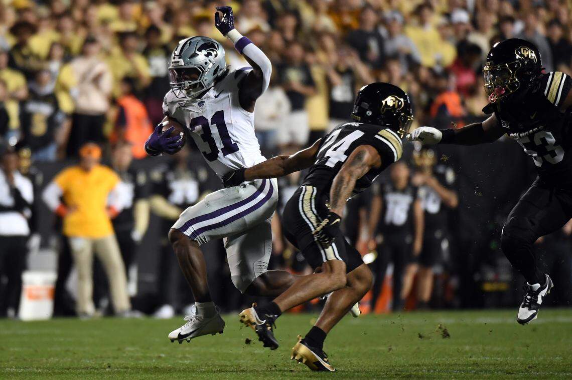 Kansas State Wildcats running back DJ Giddens, left, breaks a tackle en route to a big gain during Saturday night’s Big 12 football game against the Colorado Buffaloes at Folsom Field in Boulder, Colo.