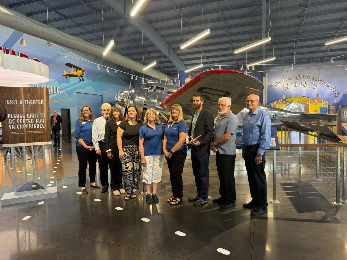 Panelists, along with employees of the Amelia Earhart Hangar Museum, pose for a picture in front of Muriel, the museum’s Lockheed Electra 10-E. The panelists gathered for a tour of the museum Friday morning.