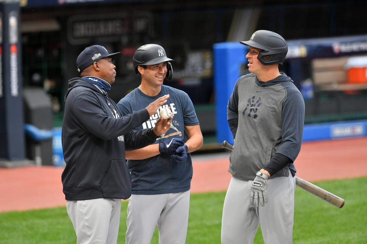 Hitting coach Marcus Thames #62 jokes with Kyle Higashioka #66 and Erik Kratz #38 of the New York Yankees prior to Game 2 of a Wild Card series against Cleveland at Progressive Field on September 30, 2020 in Cleveland.