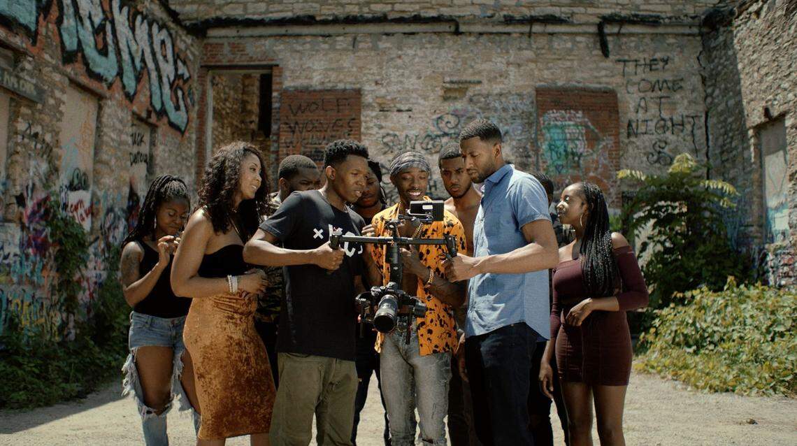 A rapper (Petey McGee, center) looks at some footage of his music video, shot by Kansas City filmmaker Moji (Denzel Whitaker) in “U Shoot Videos?”