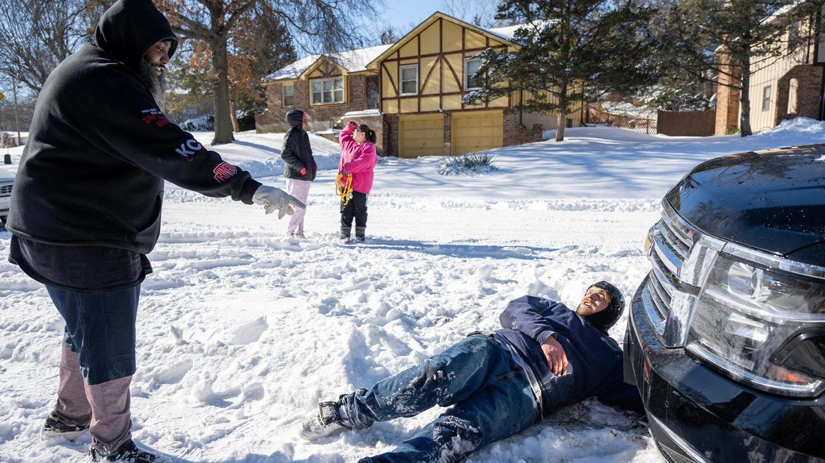 Kendall Amos, left, watches as Corey Sutton, right, secures a rope to his vehicle to pull it out of a snowbank on Tuesday afternoon in Kansas City, Kansas. Sutton and his wife, Summer Gifford, rear right, started helping people in need during the blizzard on Saturday night and have yet to stop.