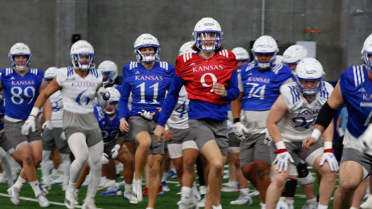 Kansas redshirt-senior quarterback Jason Bean (9) joins his team in warmups during a spring practice at the Jayhawks’ indoor practice facility.