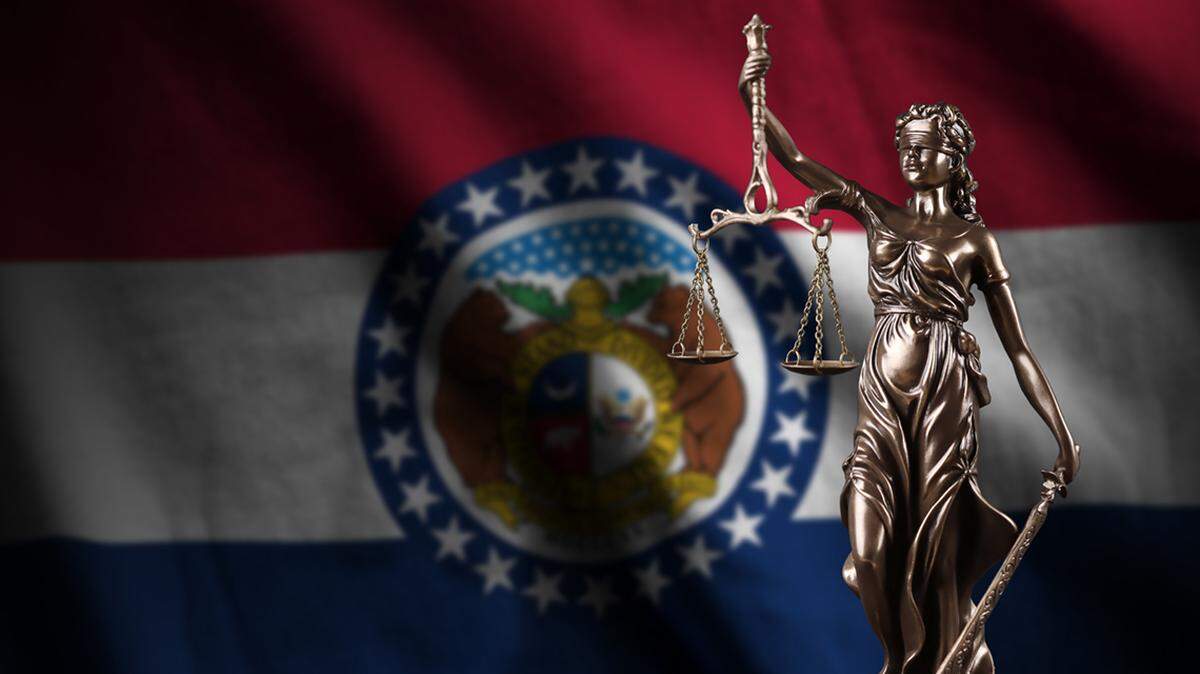 Missouri US state flag with statue of lady justice and judicial scales in dark room. Concept of judgment and punishment, background for jury topics crime criminal justice record 