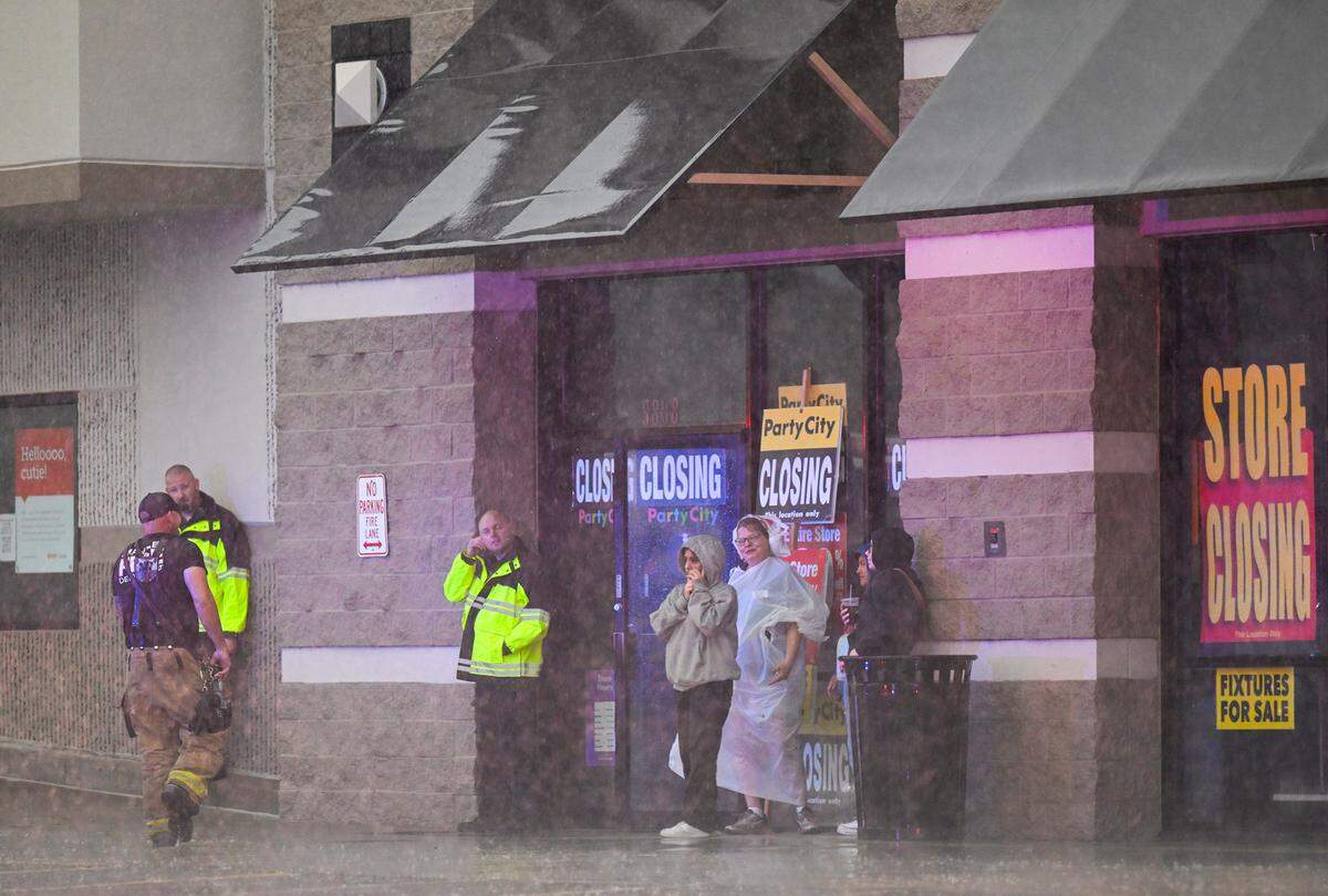 People huddled outside of a Party City store after power was knocked out when a severe storm moved through Merriam, Kansas, on Friday, July 14, 2023.