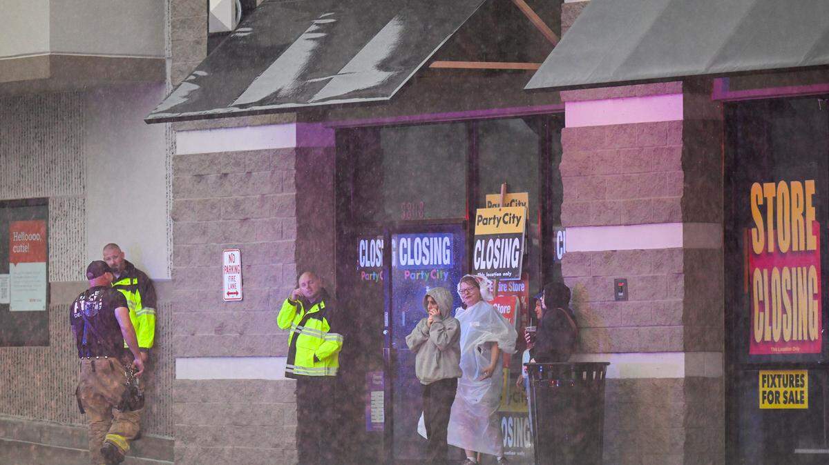 People huddled outside of a Party City store after power was knocked out when a severe storm moved through Merriam, Kansas, on Friday, July 14, 2023.