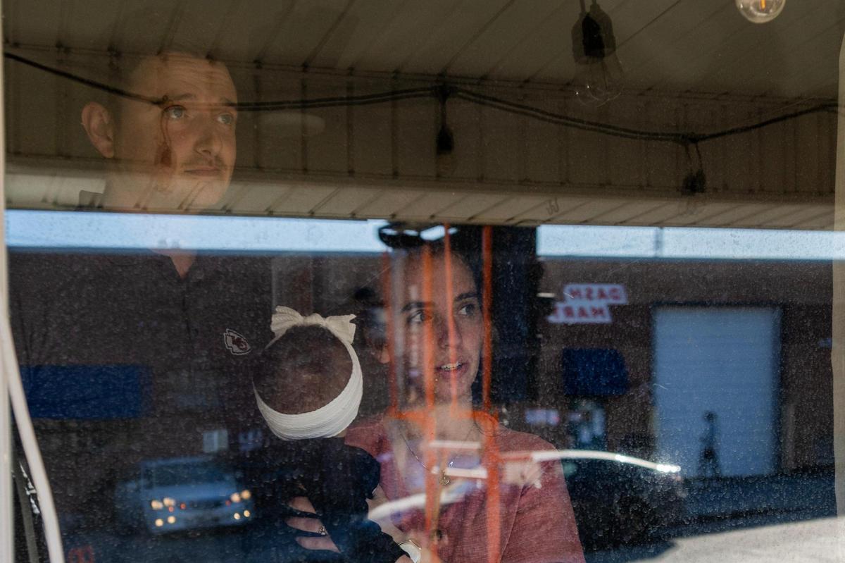Midtown residents John and Sarah Wildman stand for a portrait, looking out their window that faces DashMart on Thursday, Feb. 27, 2025, in Kansas City.