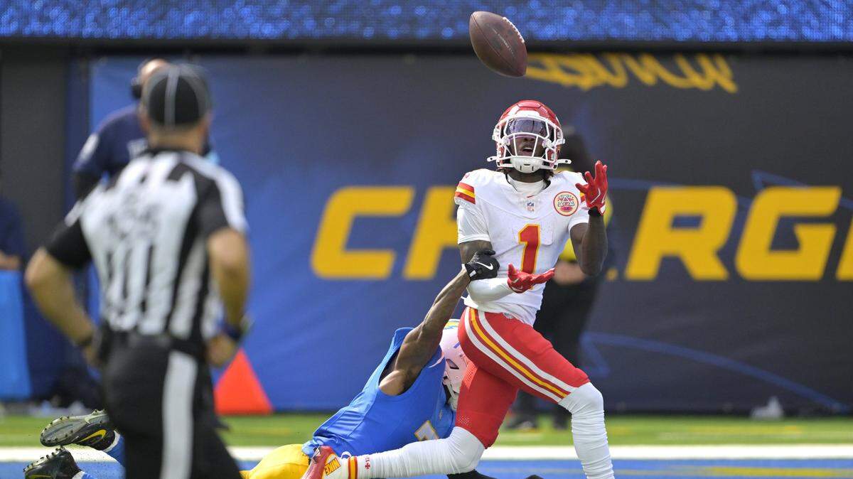 Kansas City Chiefs wide receiver Xavier Worthy (1) is defended by Los Angeles Chargers cornerback Kristian Fulton (7) as he hangs on to a touchdown pass in the first half at SoFi Stadium on Sunday, Sept. 29, 2024.