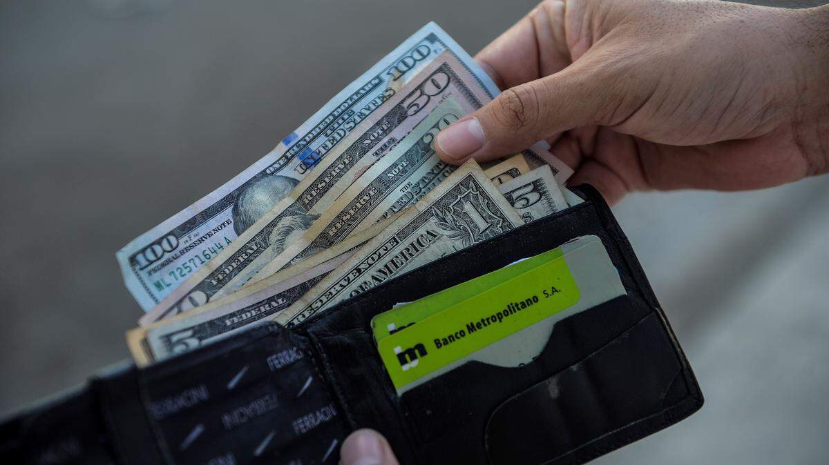 a man looks at his wallet. (Photo by YAMIL LAGE / AFP) (Photo by YAMIL LAGE/AFP via Getty Images)
