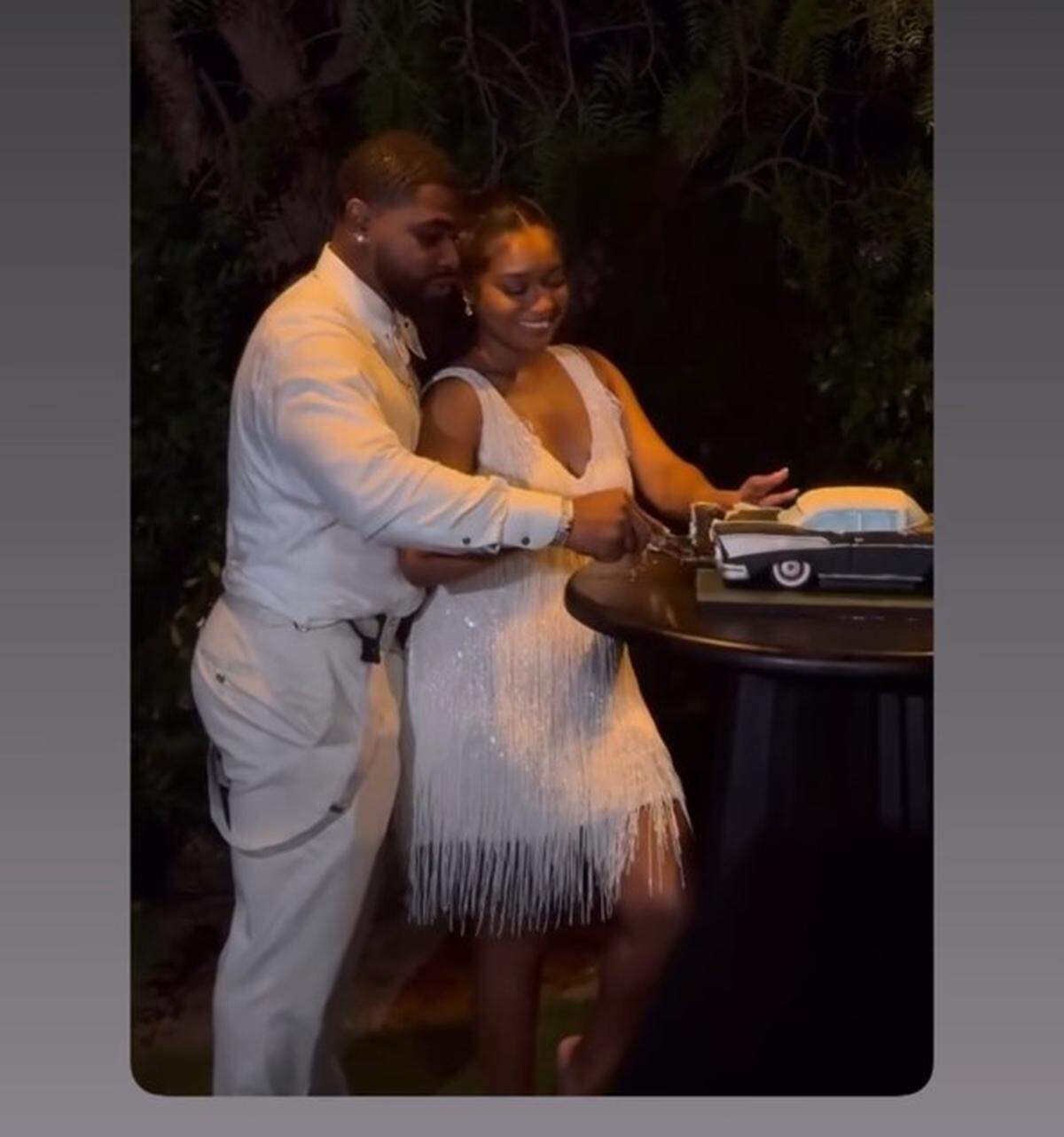 The bridge and groom cut a cake that was in the shape of a car.