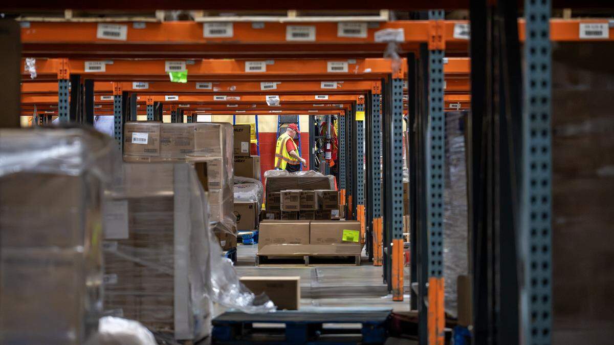 A staff member walks by partially empty shelves inside the Harvesters food bank warehouse on Tuesday, Oct. 28, 2025, in Kansas City. 
