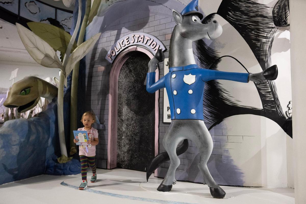 Sloane Baisden, 2, of Kansas City, picks up a copy of “Robert the Rose Horse” next to its exhibit.