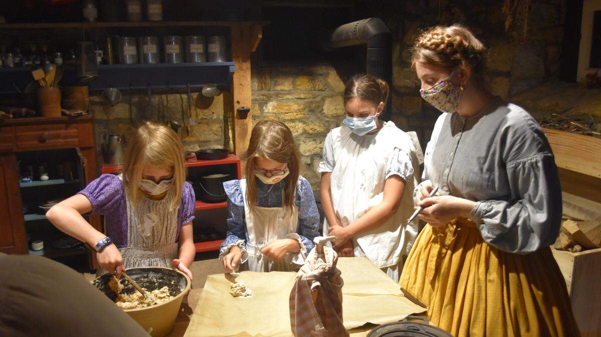 Madelyn Vogelbacher, Lydia Thrasher and Lyla Gatza learn to make biscuits in the 1860s style with historical interpreter Alyse LaPorte.