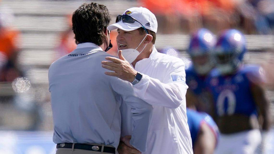 Kansas Jayhawks football coach Les Miles, right, talks with Oklahoma State coach Mike Gundy before Saturday’s game in Lawrence, Kan.