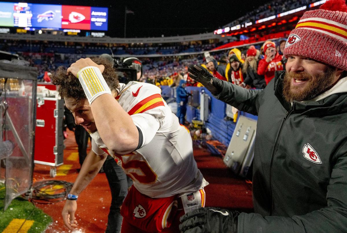 Kansas City Chiefs quarterback Patrick Mahomes shields himself from snowballs thrown by Buffalo Bills fans after he gave his headband to a young fan in the stands Sunday at Highmark Stadium in Orchard Park, New York. Mahomes had just led his team to a 27-24 win over the Bills in the AFC Divisional playoff game.