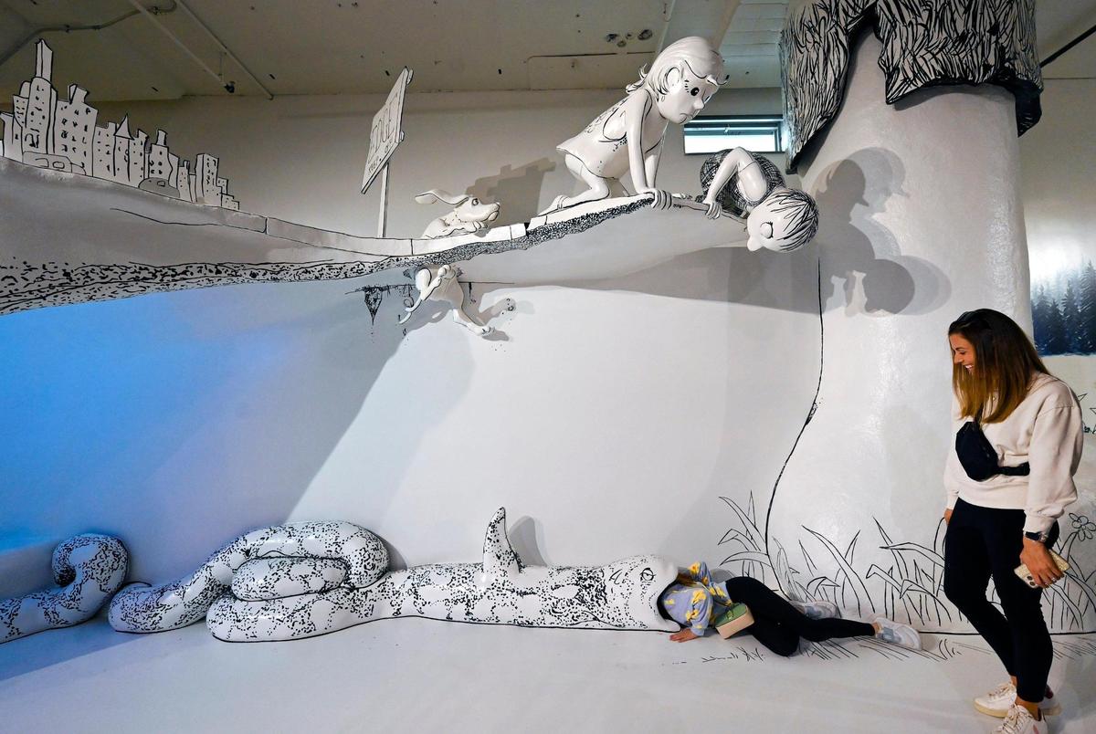 A visitor sticks her head into the mouth of a snake, part of the exhibit based on “Where the Sidewalk Ends,” by Shel Silverstein.
