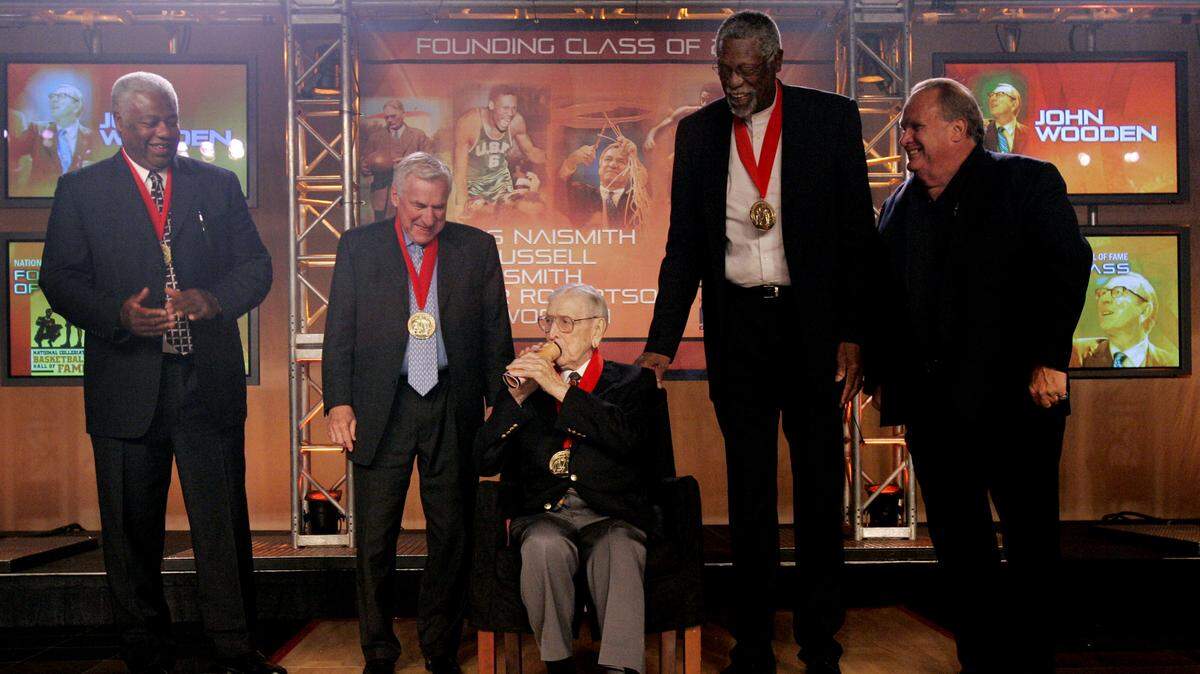 In this 2006 file photo, coaching legend John Wooden (center) showed how he rolled his program into a megaphone while he shared the stage with fellow inaugural National Collegiate Basketball Hall of Fame inductees (from left) Oscar Robertson, Dean Smith and Bill Russell, and Ian Naismith, grandson of posthumous inductee James Naismith.