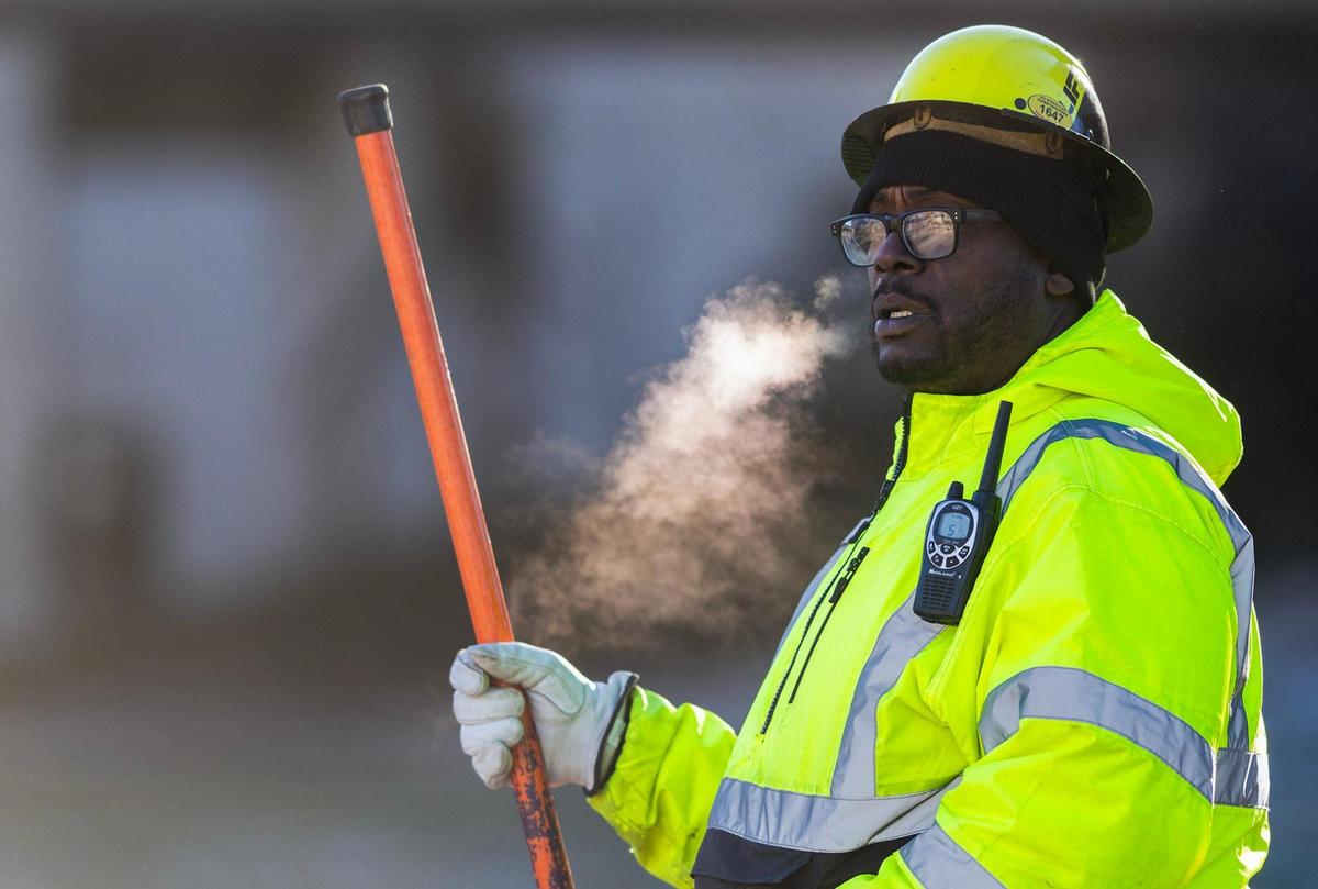 One day after temperatures hit the mid-70s, Jason Rushing of Rising Construction, was bundled against the bitter cold as he worked traffic control on the KC Streetcar expansion along Main Street near Pershing Road on Feb. 28, 2024, in Kansas City.