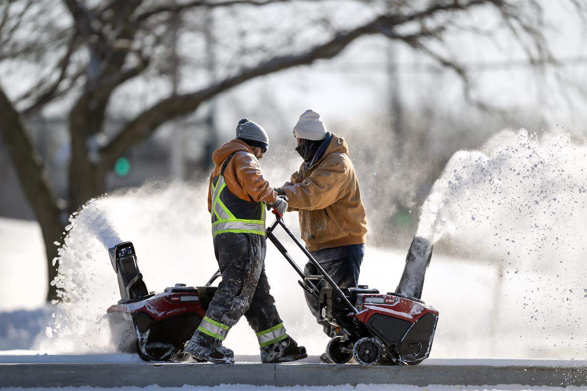 Rodrigo Cruz, left, and Caesar Walters operated snow blowers as they cleared snow from the sidewalks at the Quivira 95 Shops on Sunday, Jan. 25 2026, in Lenexa. Cruz said the crew had been out clearing snow since 3 a.m. Saturday.