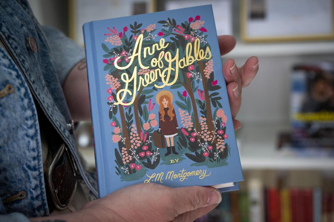 Kara Bowersock displays an edition of “Anne of Green Gables” by L.M. Montgomery that she carries in Smitten Booktique, her mobile bookstore located in a 20-foot cargo trailer.
