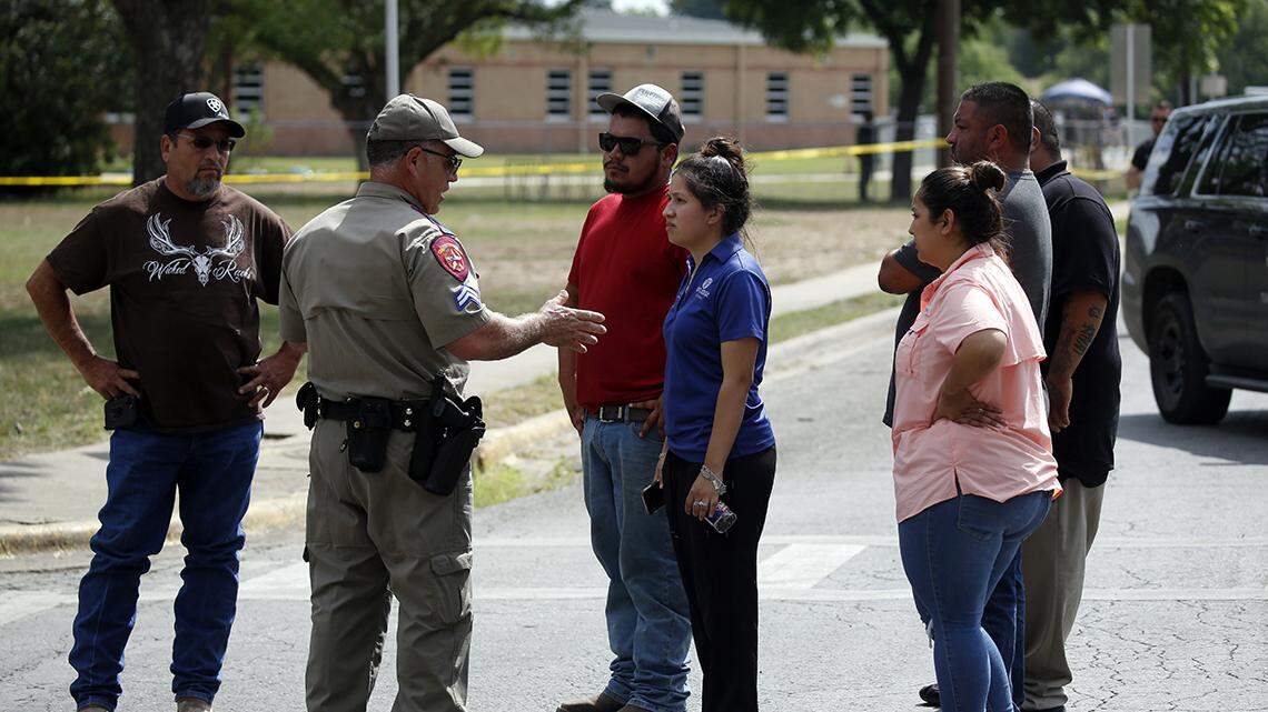 A policeman talks to people asking for information outside of the Robb Elementary School in Uvalde, Texas, Tuesday, May 24, 2022.