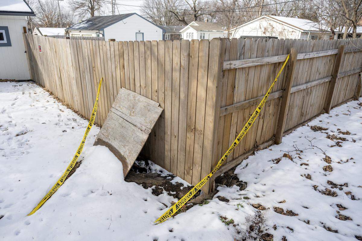 A sinkhole along a fence line in the backyard of Cassandra Krul's home is covered with a piece of plywood and marked off with caution tape on Monday, Feb. 2, 2026, in Independence.
