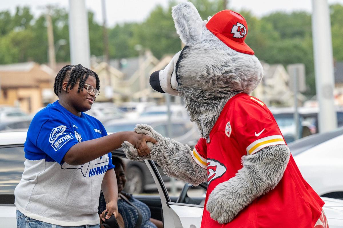 Kansas City Chiefs mascot K.C. Wolf greets a student getting out of a car to welcome them on their first day of school at Central High School on Monday, Aug. 19, 2024, in Kansas City.