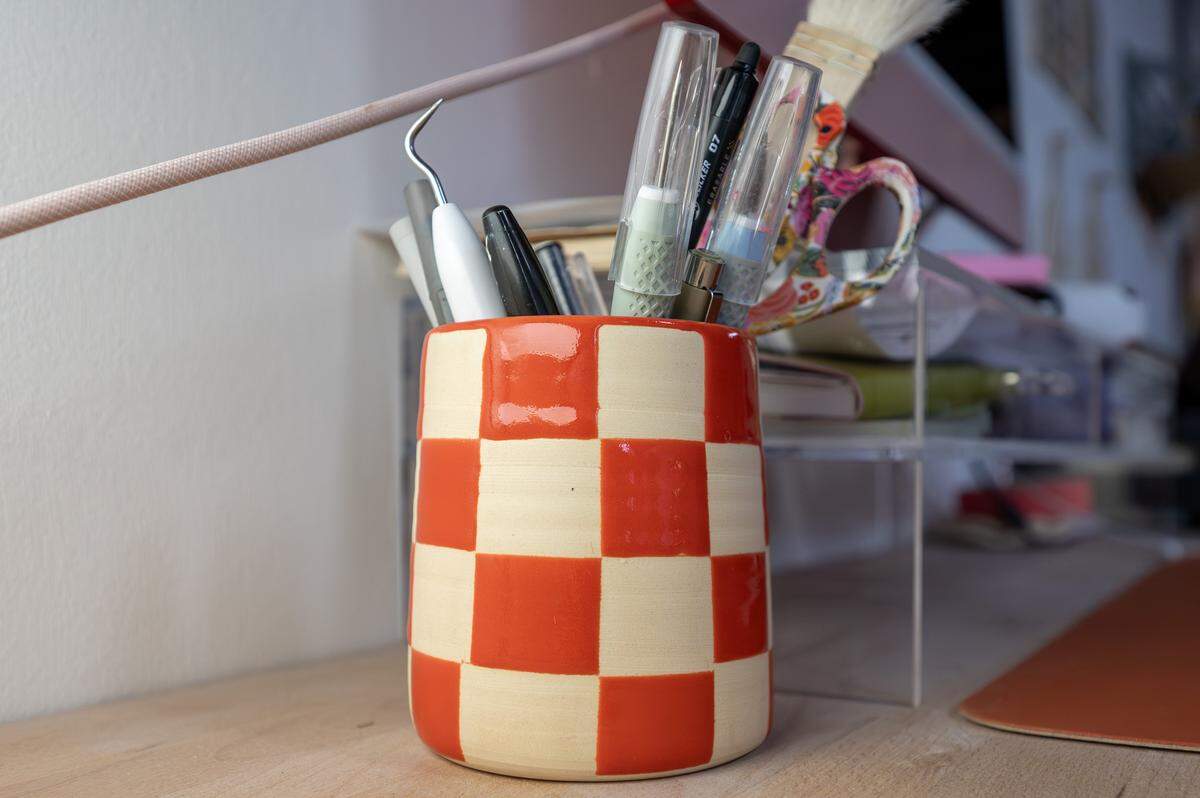 A checkered ceramic mug made by ceramicist Priscilla Butler, holding pens and other utensils, is seen at her studio, Lila's Clayground, on Thursday, Jan. 29, 2026, in Kansas City.