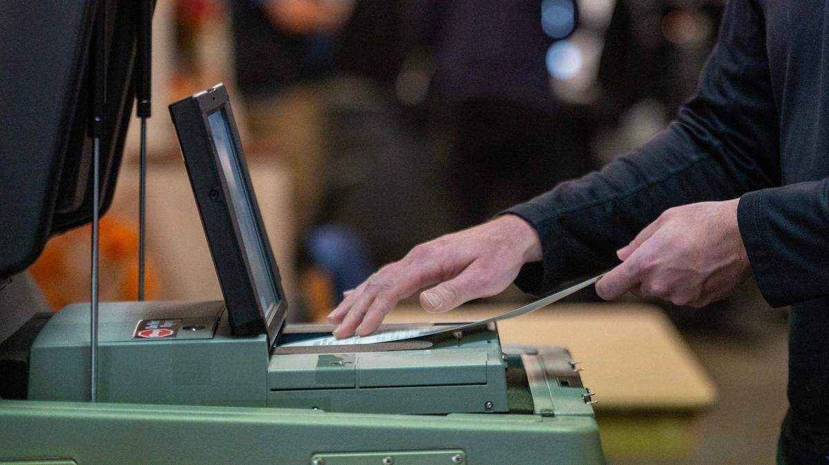 A voter cast their ballot into a voting machine at Asbury United Methodist Church on Tuesday, Nov. 7, 2023, in Prairie Village.