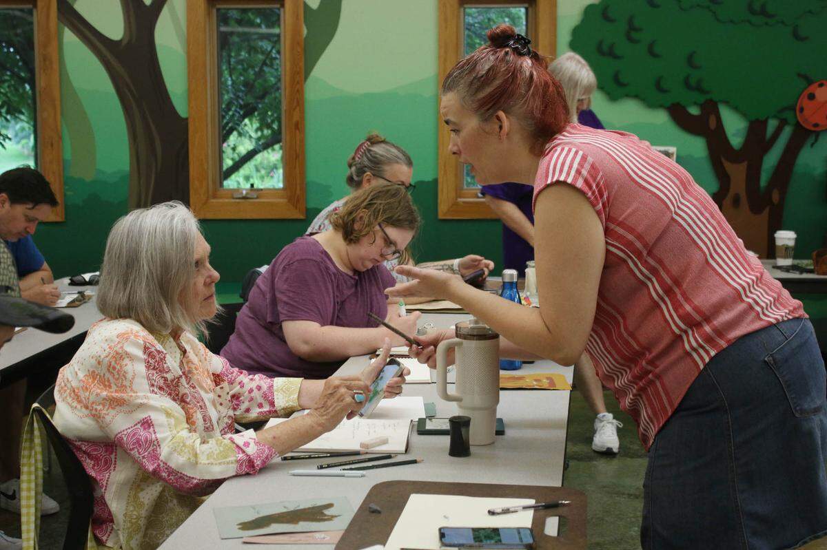 Overland Park resident Karen Mendenhall chats with artist Jill Tichenor about art supplies during the herb drawing class at the OVerland Park Arboretum.