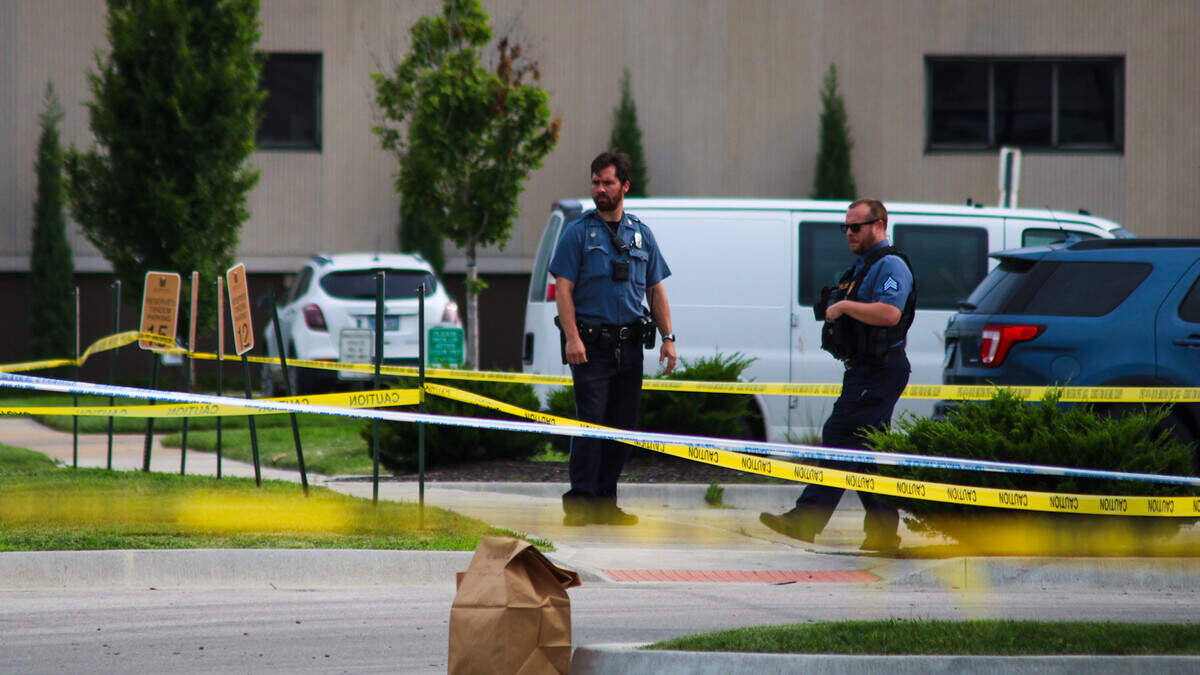 Officers secure the scene of a homicide where a man was found dead in the back parking lot of Midtown Plaza Apartments on June 12, 2025.