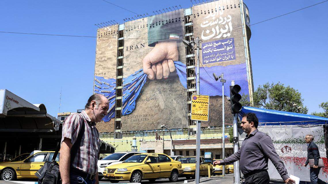 Iranians walk past a large billboard referring to the Strait of Hormuz in Tehran's Vanak Square on April 15.