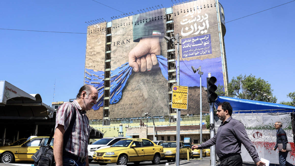 Iranians walk past a large billboard referring to the Strait of Hormuz in Tehran's Vanak Square on April 15.