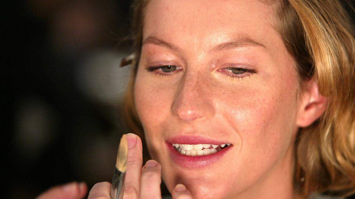 a model gets makeup done at a fashion show.