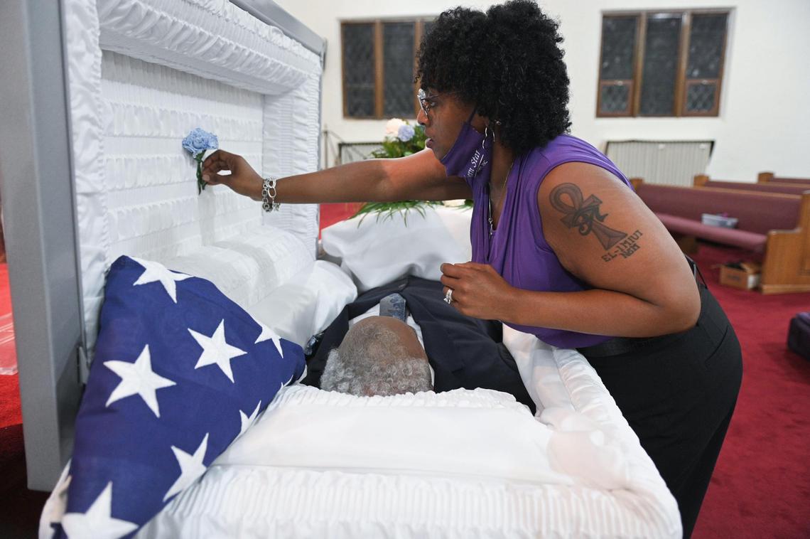 Mortician Gwendelrae Hicks pins a carnation inside the casket of Charles Watkins before his funeral at Paseo Baptist Church in Kansas City.