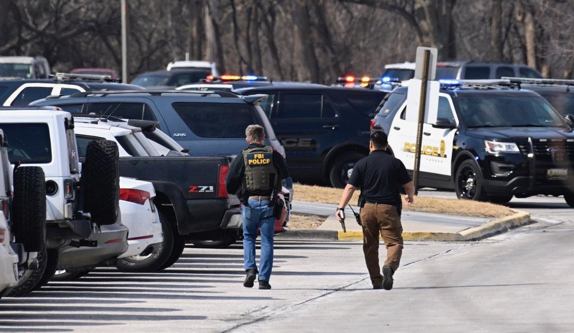 Law enforcement officers, including an FBI agent, gathered in the Olathe East High School parking lot shortly after the March 4 shooting at the school.