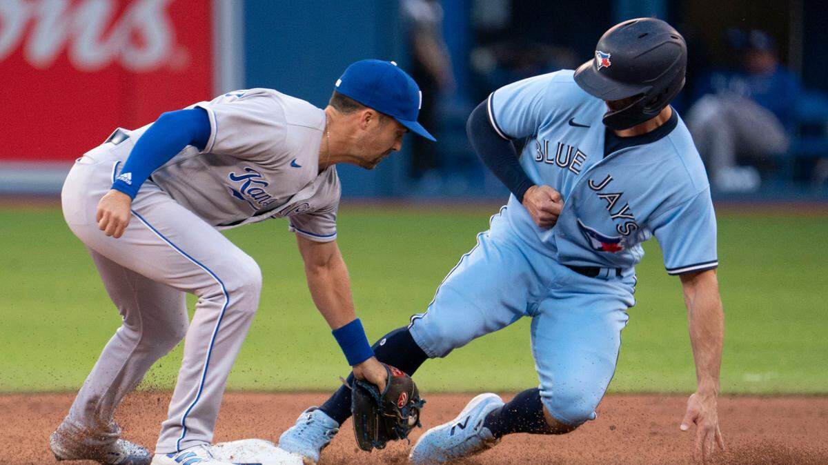 Toronto Blue Jays’ Randal Grichuk (15) beats the tag by Kansas City Royals second baseman Whit Merrifield (15) at second base after a wild pitch during the second inning of a baseball game Friday, July 30, 2021, in Toronto. The Blue Jays were playing in Toronto for the first time since the COVID-19 pandemic began. (Peter Power/The Canadian Press via AP)