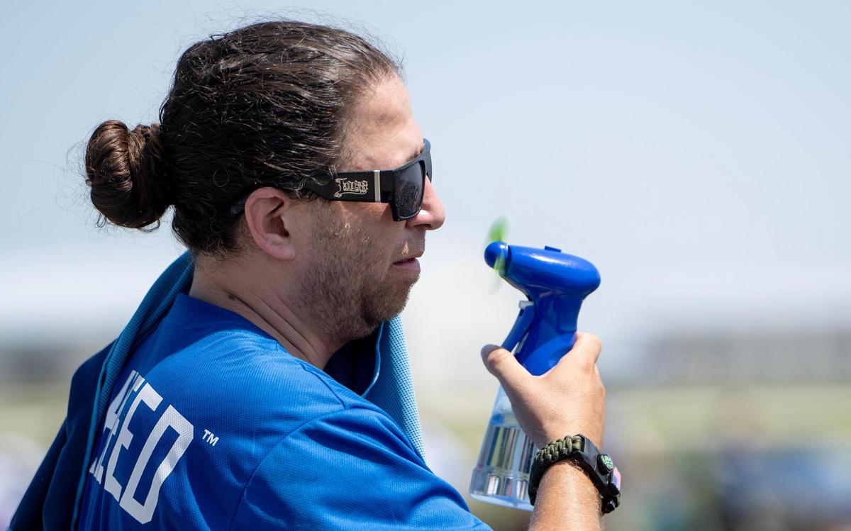 Tim Zabala of Topeka, Kan., uses a fan to try to keep cool during the Garmin KC Air Show on Saturday, Aug. 19, 2023, in New Century, Kan.