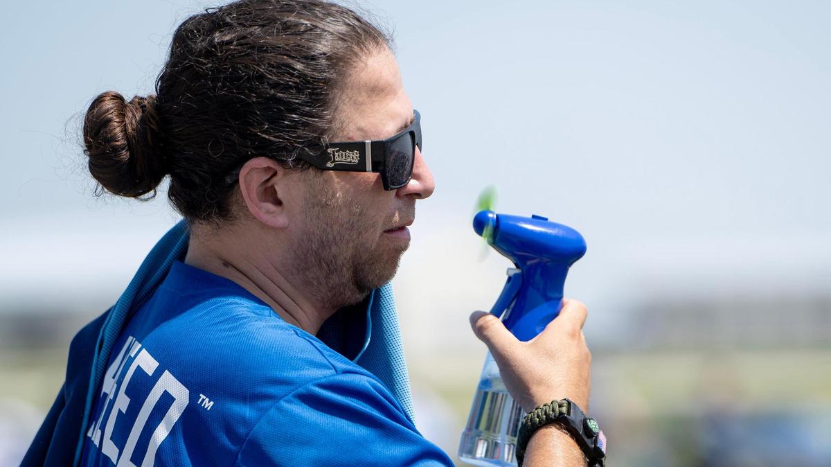 Tim Zabala of Topeka, Kan., uses a fan to try to keep cool during the Garmin KC Air Show on Saturday, Aug. 19, 2023, in New Century, Kan.