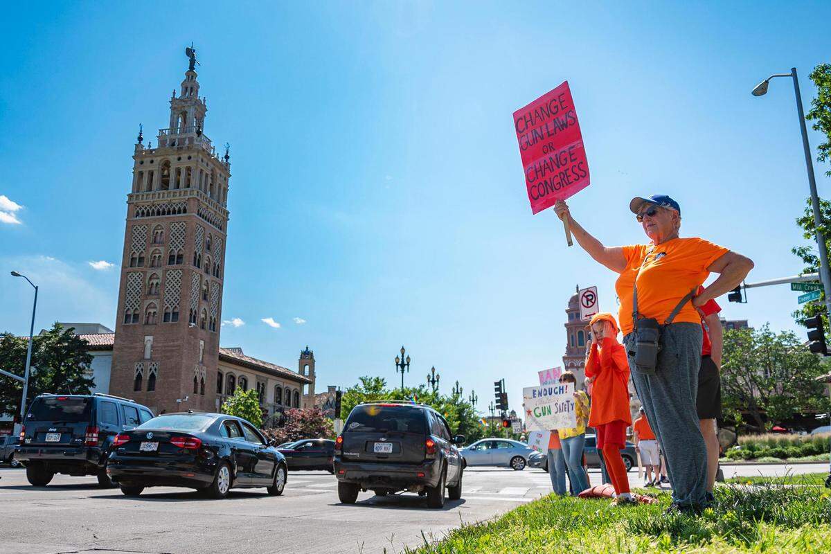 Kathleen Strange, a member of Grandparents for Gun Safety, holds a sign for passing motorists to see as people gather at the Plaza Fountain at Mill Creek Park on Friday for a peaceful demonstration focusing on the epidemic of gun violence across the United States.