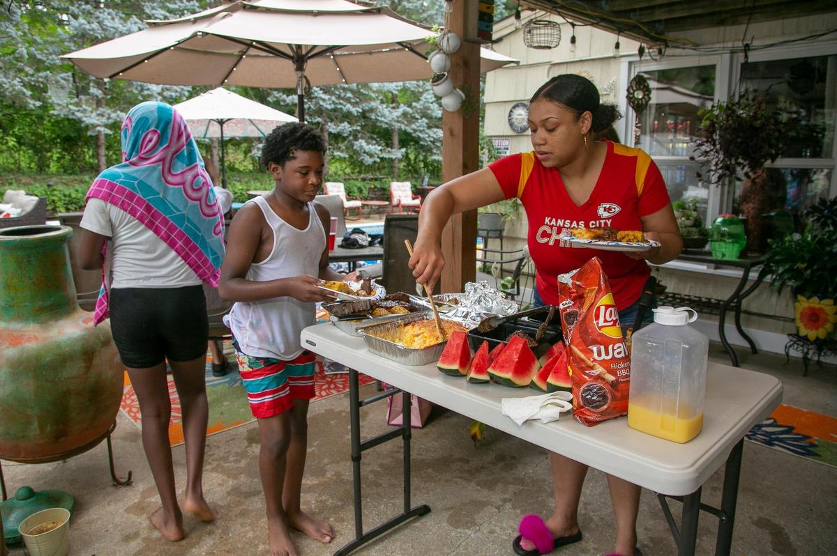 Vanessa Cowan dishes out food to her family in Deb Frey’s backyard. A family member rented the backyard pool for a few hours through the Swimply app.