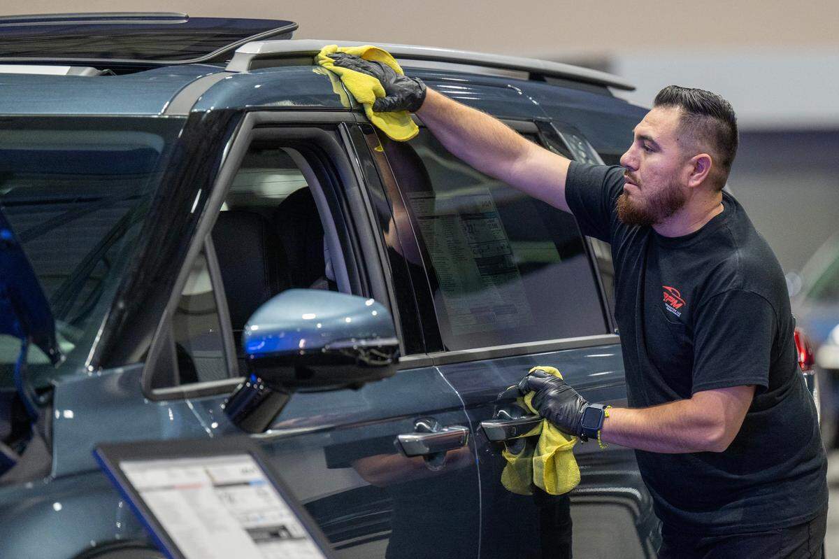 Oscar Bustillos, of Phoenix, Arizona, a member of RPM, uses a microfiber towel to wipe down a Kia automobile while preparing for the Kansas City Auto Show at Bartle Hallr on Wednesday, March 13, 2024.