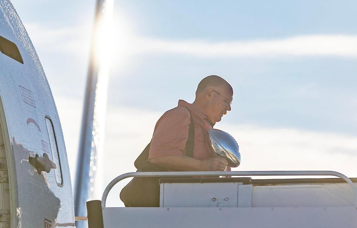 Chiefs head coach Andy Reid steps off a charter flight at Kansas City International Airport on Monday holding the Super Bowl trophy. The Kansas City Chiefs returned home after defeating the Philadelphia Eagles in Super Bowl LVII in Glendale, Ariz.