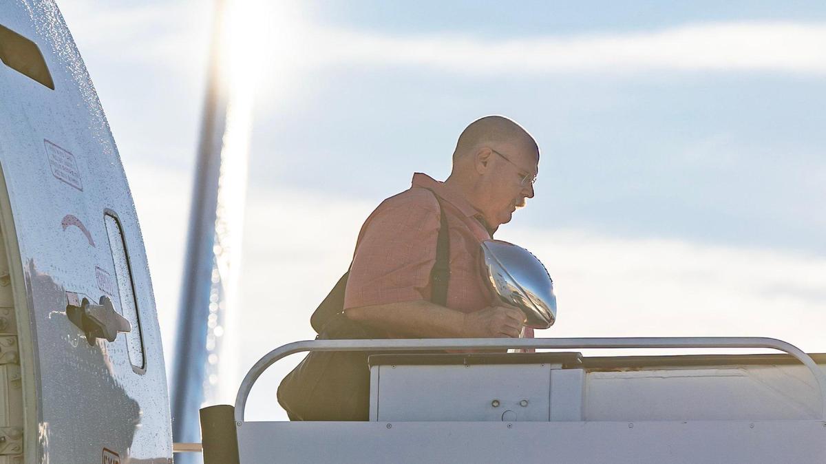 Chiefs head coach Andy Reid steps off a charter flight at Kansas City International Airport on Monday holding the Super Bowl trophy. The Kansas City Chiefs returned home after defeating the Philadelphia Eagles in Super Bowl LVII in Glendale, Ariz.