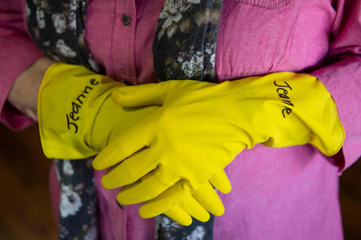 Jeanne Mackay wears rubber gloves while handling merchandise from her store, the Tasteful Olive, in an attempt to prevent the spread of the new coronavirus.